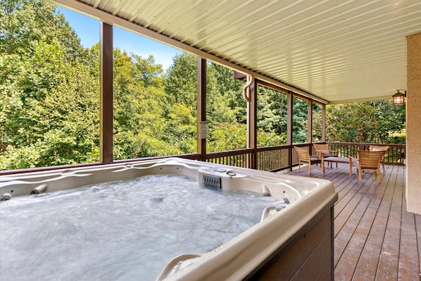 A hot tub on a wooden deck with a view of a forest.