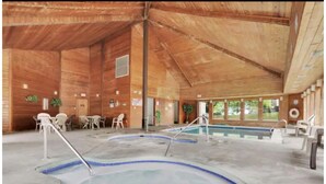 Una baita di legno con area piscina, comprensiva di vasca idromassaggio e piscina.