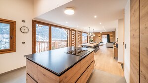 Una cucina moderna con una grande isola, mobili in legno e ampie finestre con vista sulle montagne.