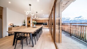 Una cucina moderna con un tavolo e sedie di legno, una grande finestra e vista sulle montagne.