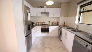 Una cocina moderna con electrodomésticos de acero inoxidable, armarios blancos y un amplio ventanal.