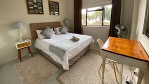 Una habitación de hotel con cama, mesitas de noche, escritorio y ventana con cortinas.
