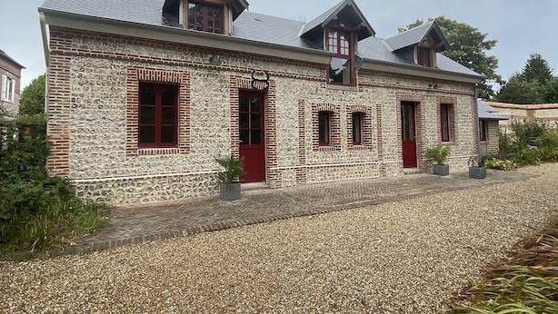 A stone building with a gravel driveway and a red door. - Gîte Les Roches D'Étigues near Etretat (Vattetot-sur-Mer)