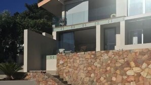Et moderne hus med to etager, en stenvæg og en træterrasse.