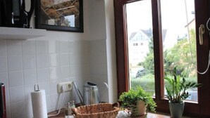 Eine Küche mit großem Fenster, Spüle, Wasserkocher und einer Pflanze.