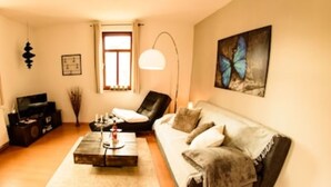 Ein Wohnzimmer mit einer Couch, einem Couchtisch, einem Fernseher und einer Lampe.