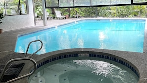 An indoor swimming pool with a hot tub, surrounded by windows and a view of greenery. - Washington State Inspired, Free Parking (Bellevue)