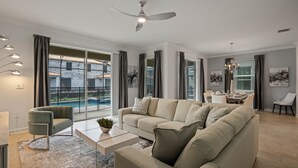 A modern living room with a sofa, coffee table, and a dining area with chairs. - 🍂 Fall Special! Bliss Pool Villa Close to Disney & Universal; Great Clubhouse🏝️ (Kissimmee)