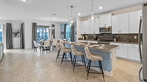 A modern kitchen with white cabinets, a central island, bar stools, and pendant lighting. - 🍂 Fall Special! Bliss Pool Villa Close to Disney & Universal; Great Clubhouse🏝️ (Kissimmee)