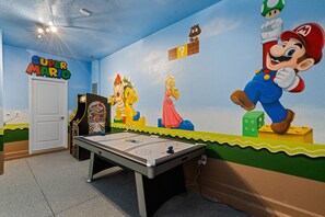 Et værelse med et poolbord, et mural af Mario og andre figurer, og et skilt med teksten "SUPER MARIO".