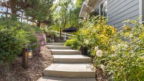 A concrete pathway leading to a house with a white fence and a black umbrella. - Hakuna Moscato - 30 day Wine Country Retreat (Temecula)