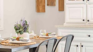 A dining area with a table set for two, featuring placemats, glassware, and a centerpiece with a plant. - Hakuna Moscato - 30 day Wine Country Retreat (Temecula)