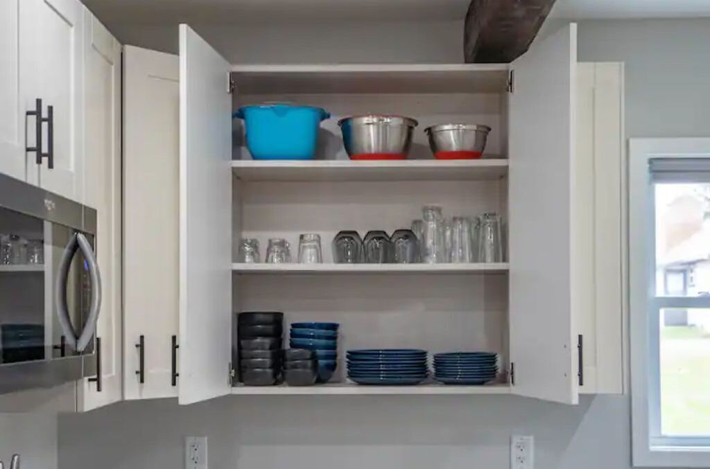 A kitchen with white cabinets, a stainless steel refrigerator, and a window with a view of the outdoors.