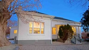 Ein eingeschossiges Haus mit Veranda, einem kleinen Vorgarten mit Kies und einem Baum links.