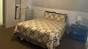 Une chambre à coucher comprenant un lit, une commode, une table de chevet et un ventilateur de plafond.