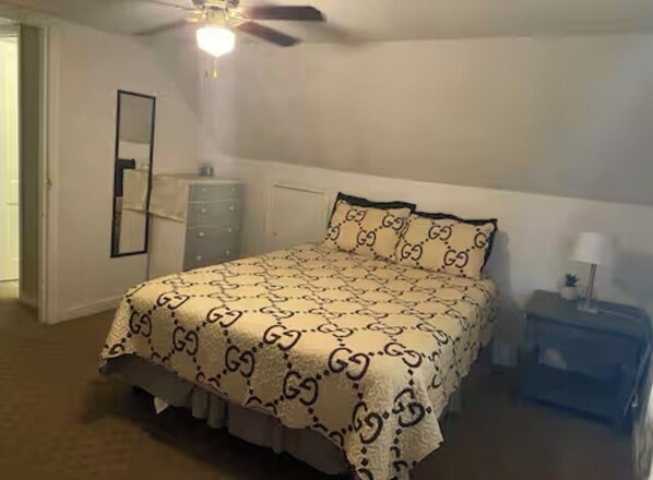 Un dormitorio con cama, cómoda, mesita de noche y ventilador de techo.