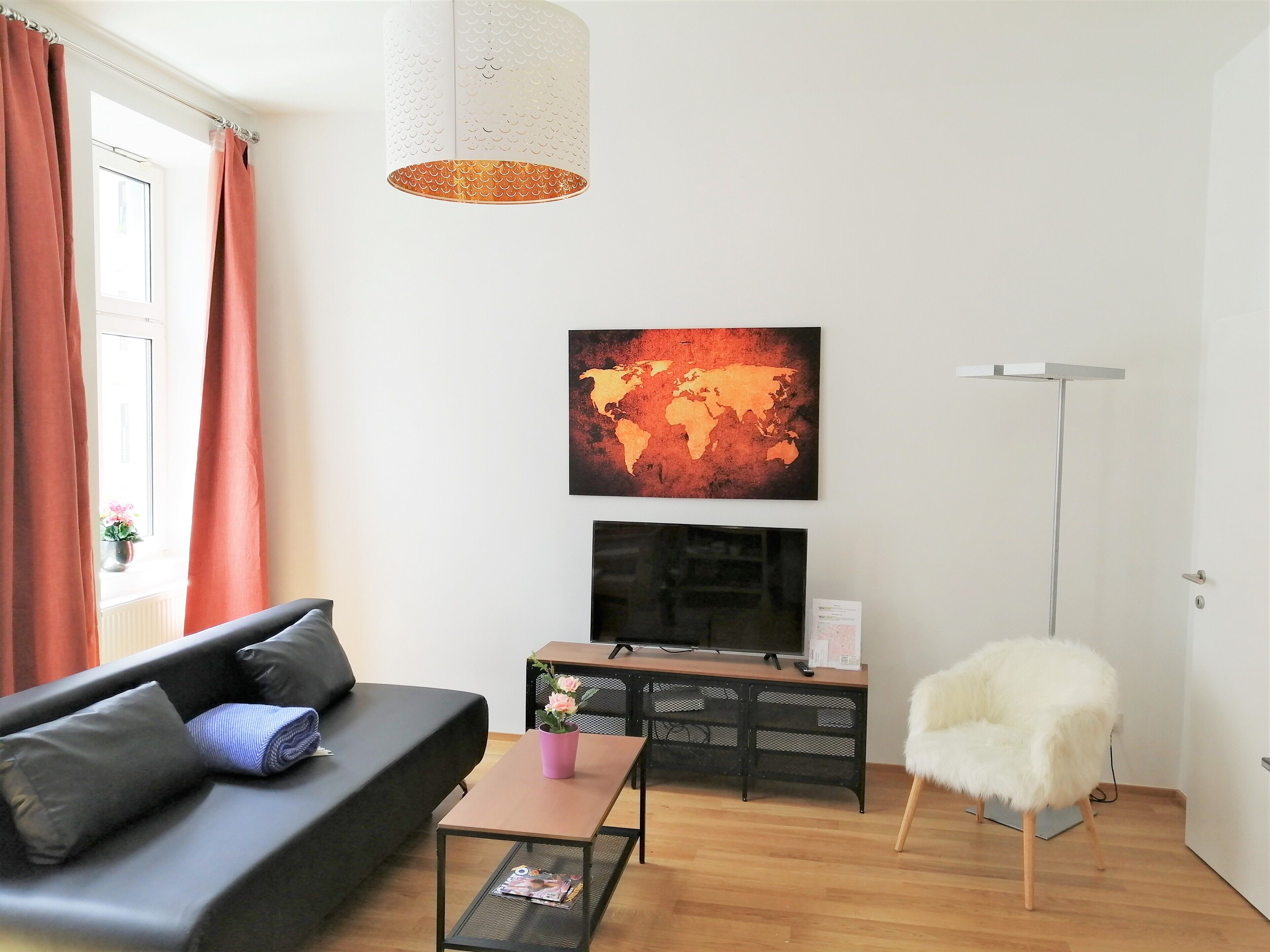 A modern living room with a black sofa, a coffee table, a white chair, a world map artwork, and a floor lamp.