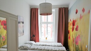 Ein Schlafzimmer mit einem Bett, einem Fenster und einem Blumenbild.