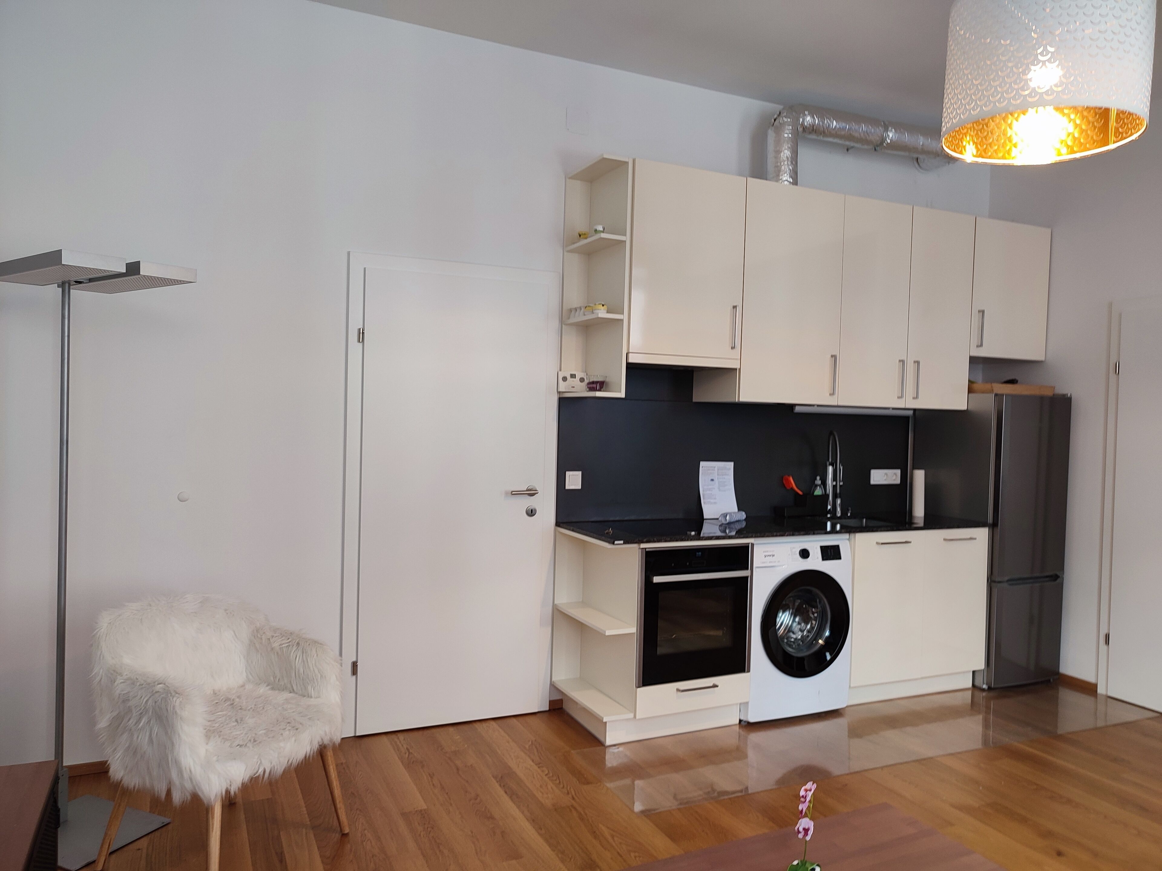 A modern kitchen with white cabinets, a washing machine, and a refrigerator.