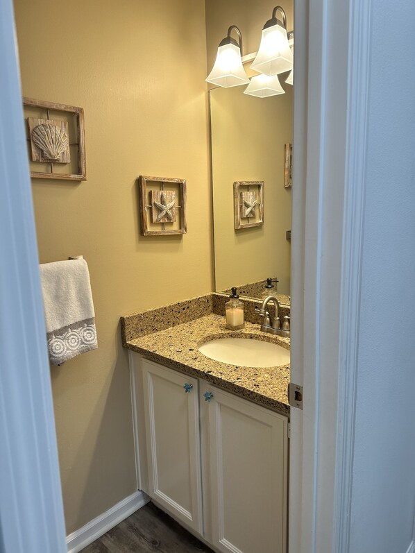 A bathroom with a granite countertop sink, a mirror, and two wall-mounted lights. - Awesome St George Island Home, Walk to Beach! PET FRIENDLY (St George Island)