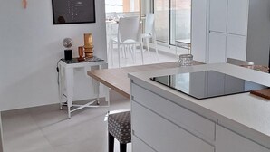 A modern kitchen with white cabinetry, a large island with a sink, and a dining area with white chairs. - Roof terrace apartment on the sea waterfront air conditioning wifi (Saint-Raphaël)