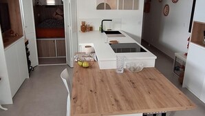 A compact kitchen with a central island, white cabinetry, and a modern pendant light fixture. - Roof terrace apartment on the sea waterfront air conditioning wifi (Saint-Raphaël)