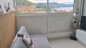 A room with a bed, a TV, a Buddha statue, and a window with a view of a landscape. - Roof terrace apartment on the sea waterfront air conditioning wifi (Saint-Raphaël)