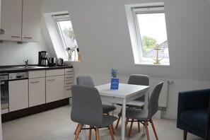 A modern kitchen with a dining area, including a coffee maker, kettle, and a welcome sign. - Bright, modern apartment with a sauna, located between the Dorf and Bad neighborhoods (Sankt Peter-Ording)