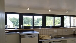 A modern kitchen with a dishwasher, a sink, and a window with a view of greenery. - House 8 pers + 1 baby - PMR access - in Monts d'Arrée. (Pets welcome!) (Brennilis)