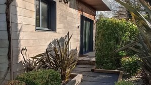 A modern house with a gravel driveway leading to a wooden door. - gite with swimming pool and beach  (Le Tour-du-Parc)