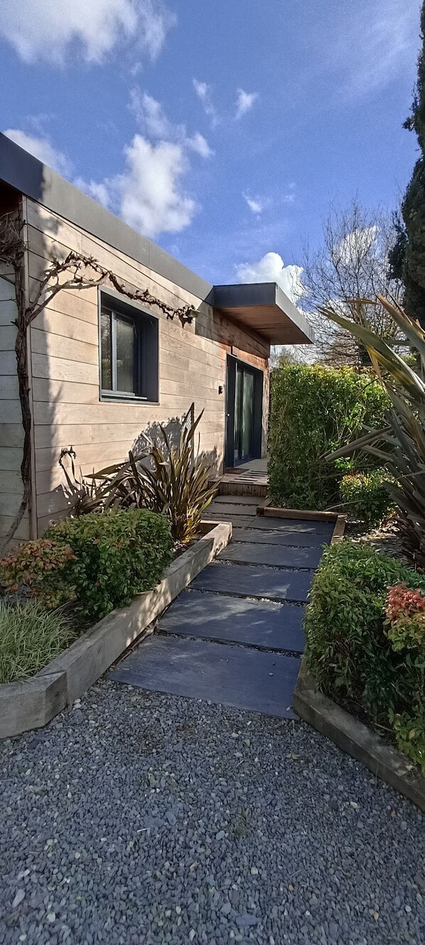 A modern house with a gravel driveway leading to a wooden door.