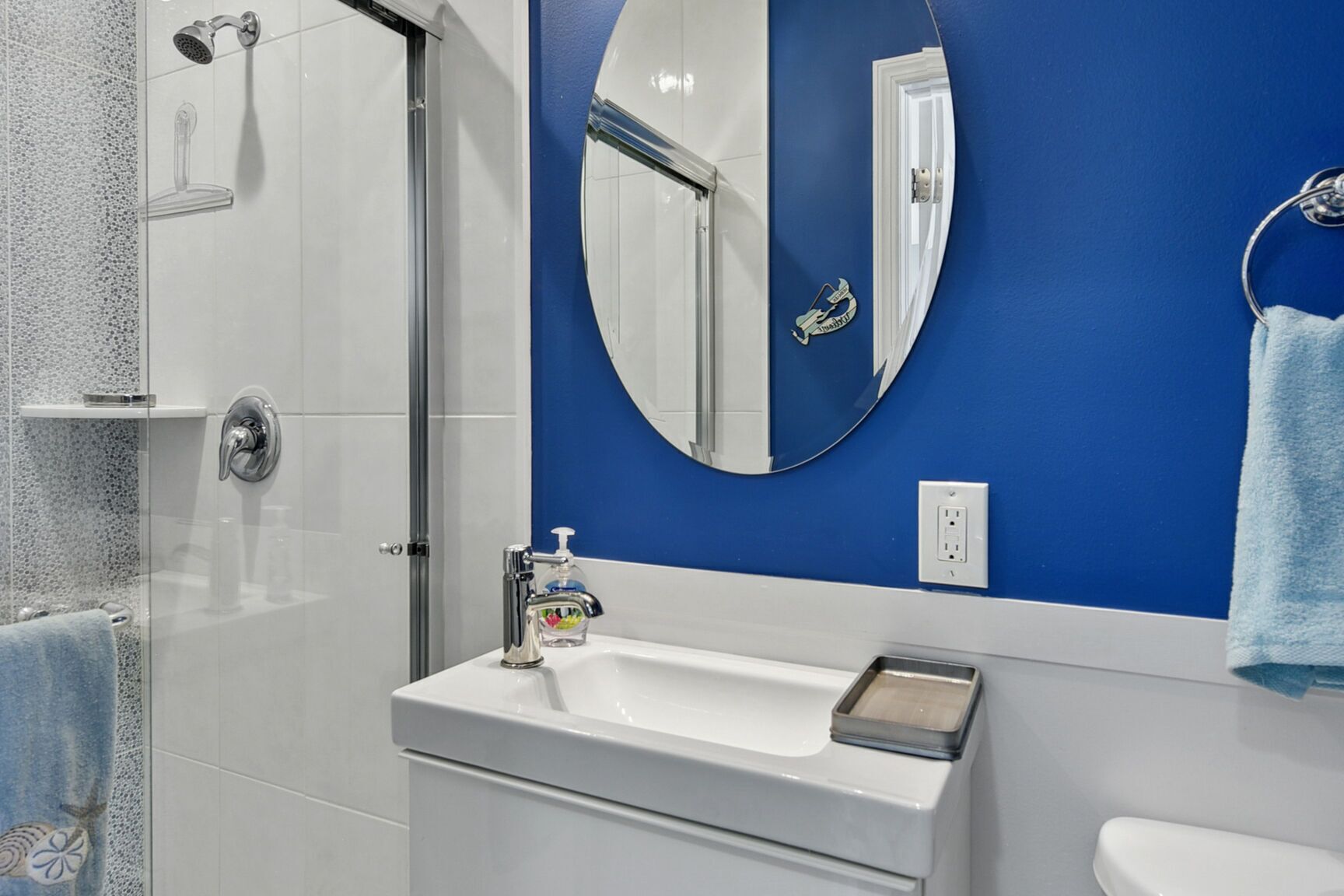 A bathroom with a white sink, a mirror, and a shower.