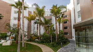 A courtyard with palm trees, a curved pathway, and modern buildings with balconies. - Serena Apartment with Terrace and Golf View (motril)