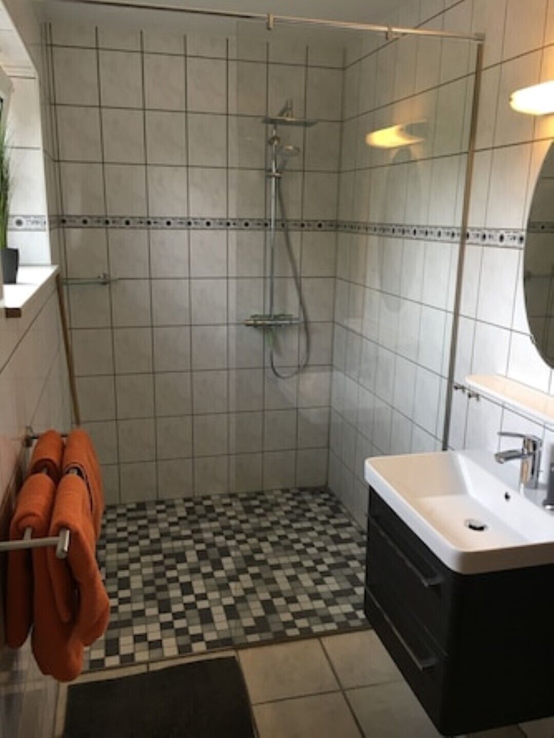 A bathroom with a shower, a sink, and a tiled floor.