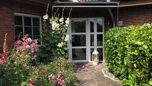Ein Haus aus Backsteinen mit Ziegeldach, einem Kiesweg und verschiedenen blühenden Pflanzen.