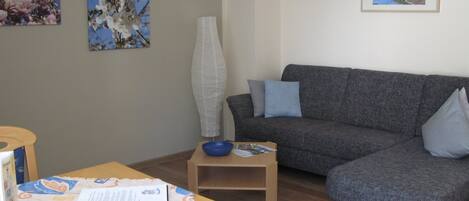 Ein Wohnzimmer mit einer Couch, einem Tisch mit einer Schale und zwei gerahmten Bildern an der Wand.