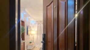 A wooden door with a keyhole, leading to a hallway with patterned wallpaper and a tiled floor. - Caribbean Golf (Punta Cana)
