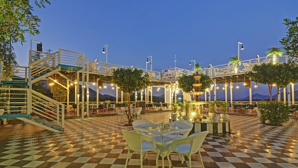 An outdoor terrace with checkered flooring, outdoor seating, and a central decorative fountain. - Treebo Khakhri Haveli (Udaipur)