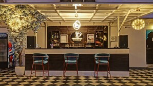 A bar area with a checkered floor, three bar stools, a decorative plant, and a sign reading "The Greenspace Bistro". - Treebo Khakhri Haveli (Udaipur)