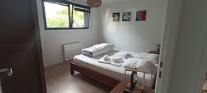 A bedroom with a bed, a window, a radiator, and artwork on the wall.