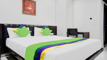A hotel room with a black headboard, white bedding, and a colorful bedspread.