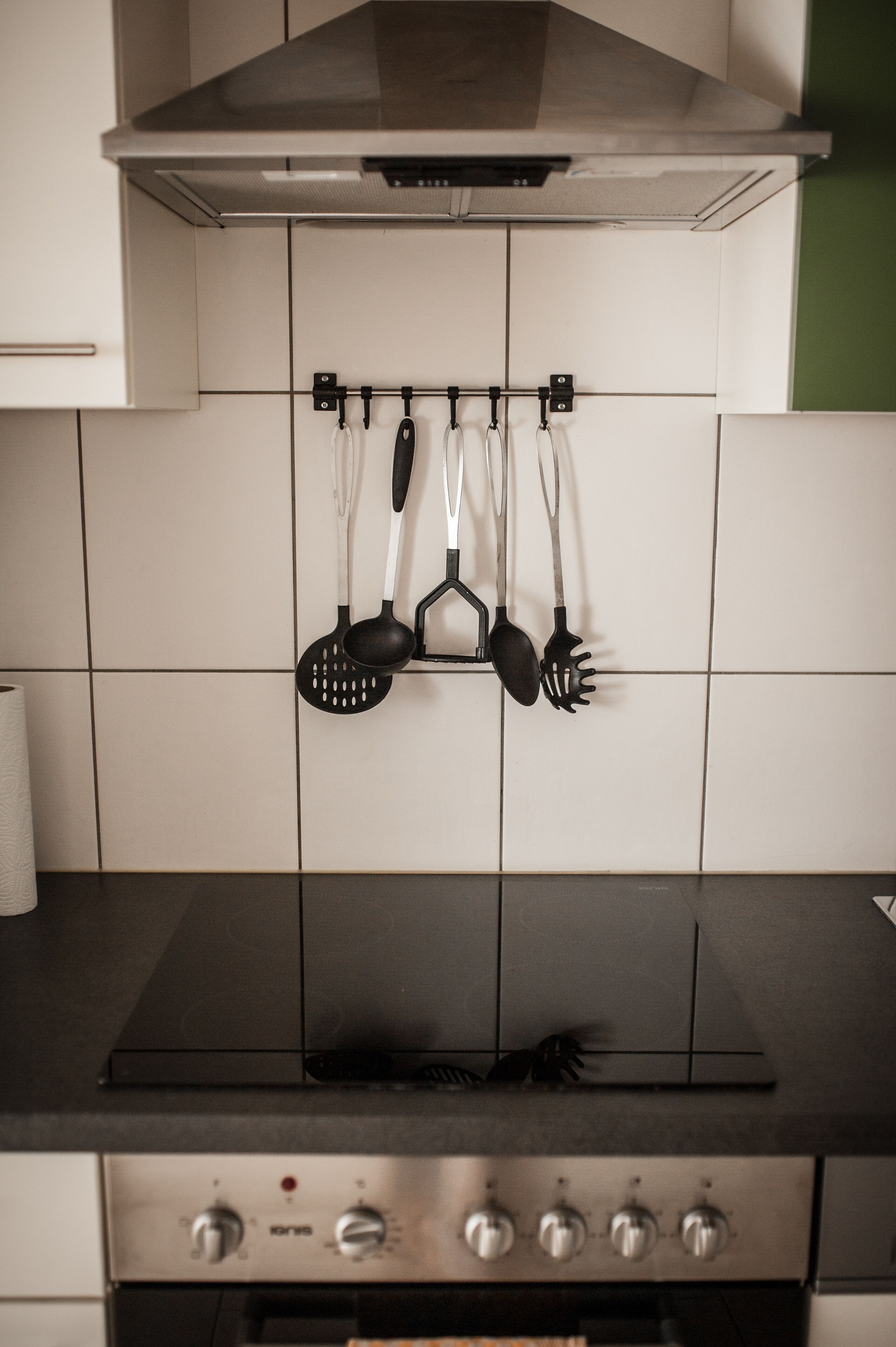 Una cocina con estufa, horno y utensilios colgados.