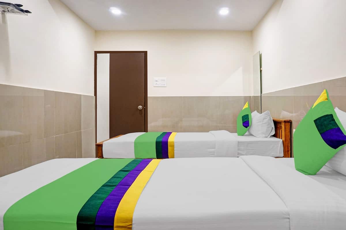 A hotel room with two beds, a door, and a mirror.