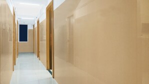 En lång, smal hall med beige väggar och ett klinkergolv. På ena sidan finns trädörrar och på den andra ett fönster.