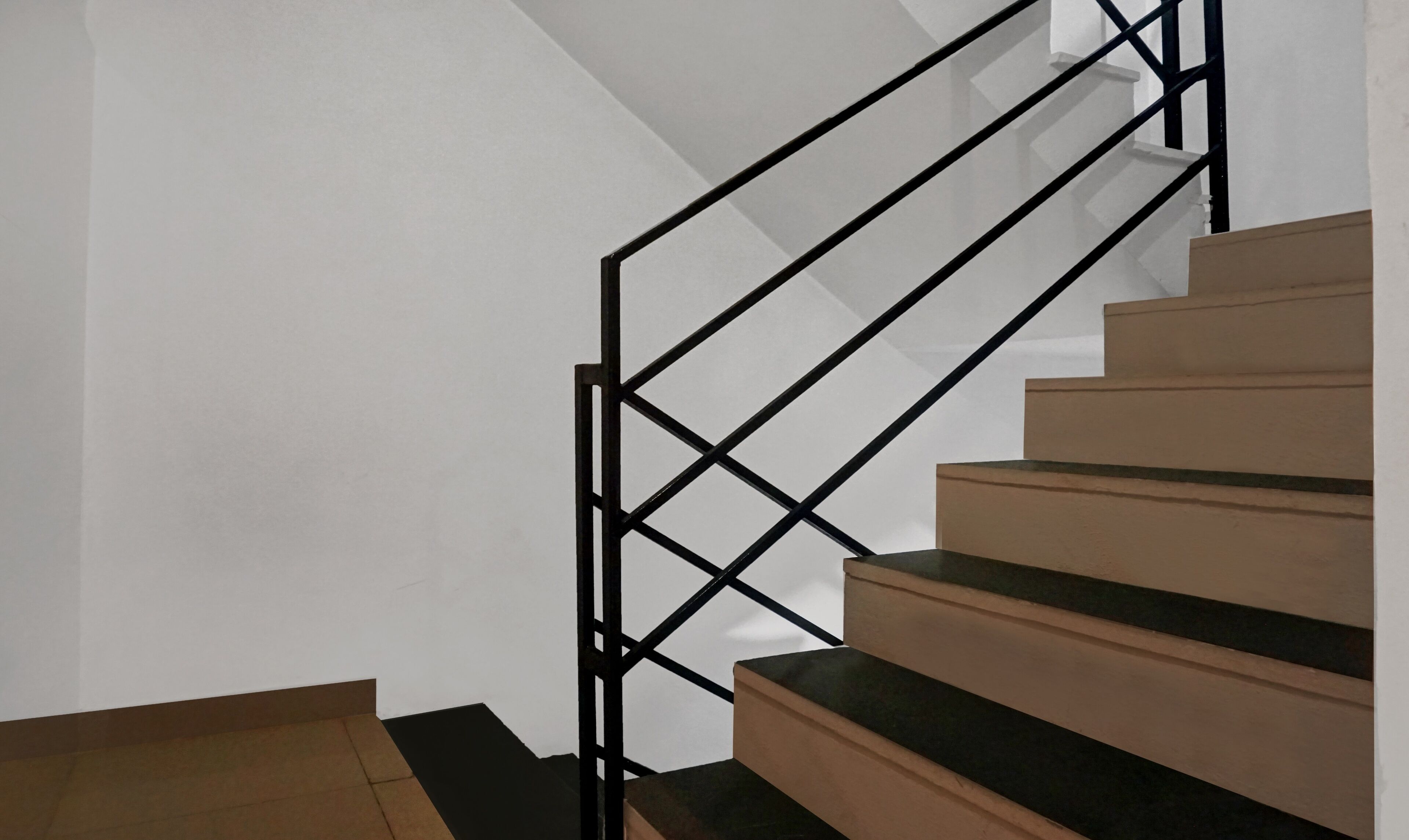 A staircase with a geometric black metal railing and wooden steps.
