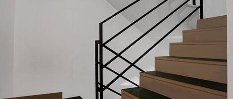 A staircase with a geometric black metal railing and wooden steps.