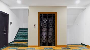 Un pasillo con una escalera que lleva a una puerta con un portón metálico.