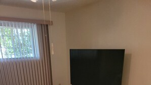 A bedroom with a large bed, a flat-screen TV on a stand, and a window with blinds. - Nice home for rent in a quiet area close to Scottsdale and Glendale  area.  Open (Sun City)