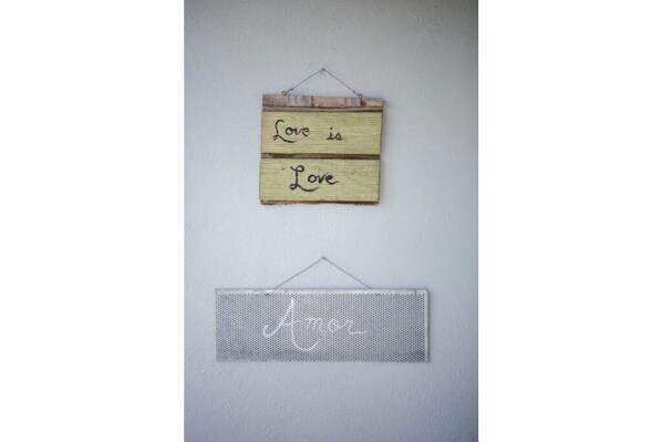 A wooden sign with the phrase "Love is Love" and a metal sign below it with the same phrase.
