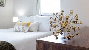 Een slaapkamer met een bed, kussens, een nachtkastje en een decoratief gouden object.